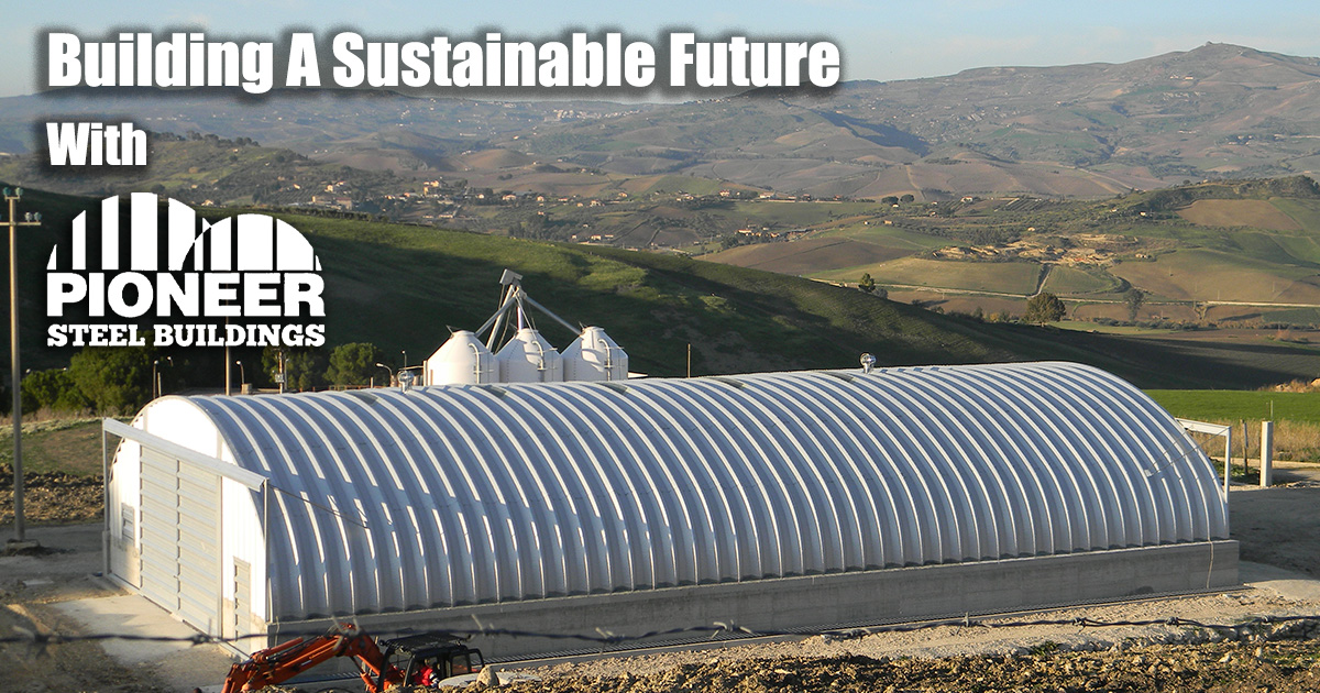 A large steel building with a few silos in the background